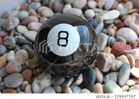 Black Billiard Ball Number Eight Lying On A Colored Smooth Pebbles Top View 129847167