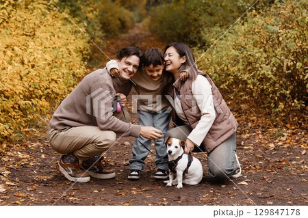 Happy family of three with dog in autumn park 129847178