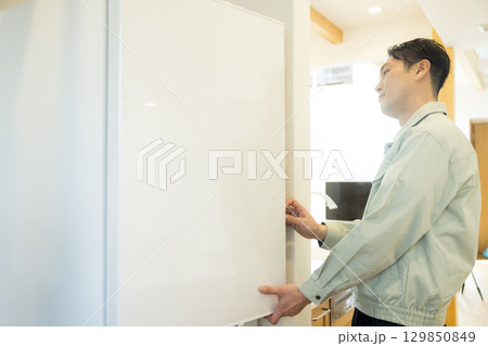 冷蔵庫設置作業する作業服の男性 129850849