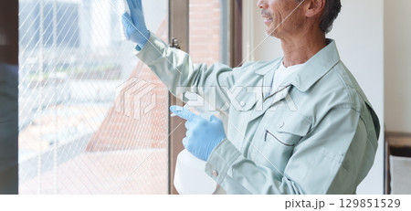 窓拭きをする清掃業者のシニア男性 窓拭きをする清掃業者のシニア男性 129851529