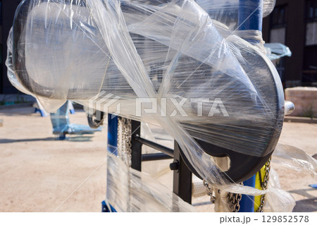 Heavy construction equipment wrapped securely for protection during transportation and storage 129852578