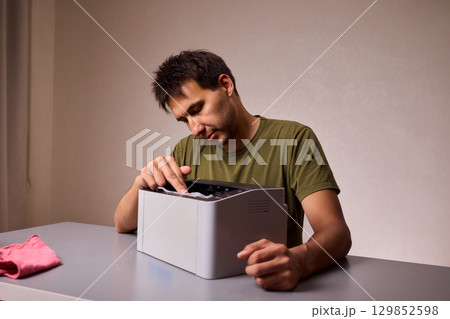 A focused man cleaning a device with a cloth for proper maintenance and cleanliness A focused man cleaning a device with a cloth for proper maintenance and cleanliness 129852598