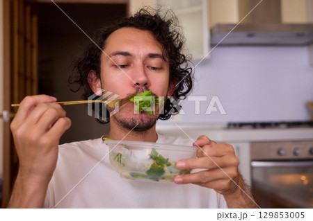 Healthy Eating A Man Enjoying Fresh Green Vegetables in a Beautiful Modern Kitchen Space 129853005