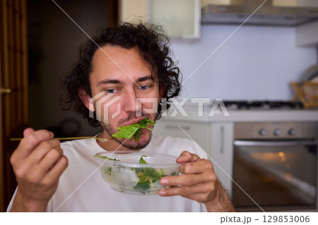 Healthy Eating A Man Enjoying Fresh Green Vegetables in a Beautiful Modern Kitchen Space 129853006