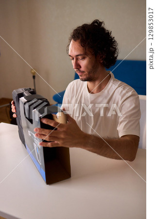 Unboxing a New Electronic Device with Great Care and Attention to Detail and Excitement Unboxing a New Electronic Device with Great Care and Attention to Detail and Excitement 129853017