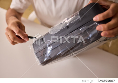 Unboxing a New Electronic Device with Great Care and Attention to Detail and Excitement 129853607