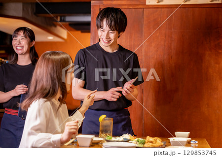 居酒屋　スマホで注文をとる男性スタッフ 129853745