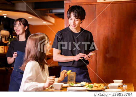 居酒屋　スマホで注文をとる男性スタッフ 129853794