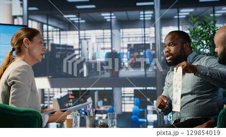 Diverse company leaders discuss business development with performance data and strategic thinking to improve career growth, executive planning and professional decision making. Camera B. 129854019