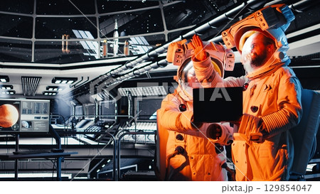 Team of astronauts shielding eyes from bright light flooding shuttle from alien vessel. Orbit station colleagues awaits first contact with extraterrestrial presence approaching 129854047