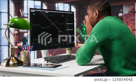 Upset broker distraught after losing money in cryptocurrency, falling for investment scam due to rug pull. Unhappy worried guy in bankruptcy crisis, financial loss after risky trade. Camera B. Upset broker distraught after losing money in cryptocurrency, falling for investment scam due to rug pull. Unhappy worried guy in bankruptcy crisis, financial loss after risky trade. Camera B. 129854048