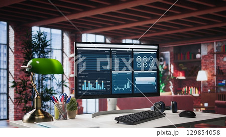 Desktop PC on the wooden desk showcases infographics and client reach data for professional use, analytics on display. Stylish, organized workspace in a bright luxurious loft home. Desktop PC on the wooden desk showcases infographics and client reach data for professional use, analytics on display. Stylish, organized workspace in a bright luxurious loft home. 129854058