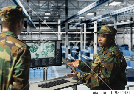 Team of military experts in data center looking at world map, coordinating mission zones. Army units in server farm looking at global map, commanding remote battlefield operations Team of military experts in data center looking at world map, coordinating mission zones. Army units in server farm looking at global map, commanding remote battlefield operations 129854481