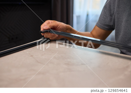 Hand Assembling a Frame on a Beautiful and Modern Table in a Creative Workspace 129854641