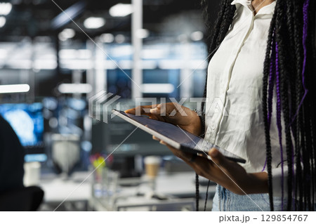 Close up of data center engineer using tablet, deploying and maintaining server and network hardware. Server hub employee using device to manage large scale IT infrastructure 129854767