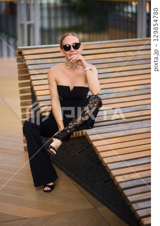 An Elegant Woman in a Stylish Outfit Stands Beautifully at Sunset, Radiating Confidence 129854780
