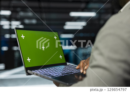 Close up of engineer in data center using isolated screen laptop to check for server performance issues. IT professional in server hub fixing errors slowing down hardware using mockup notebook 129854797