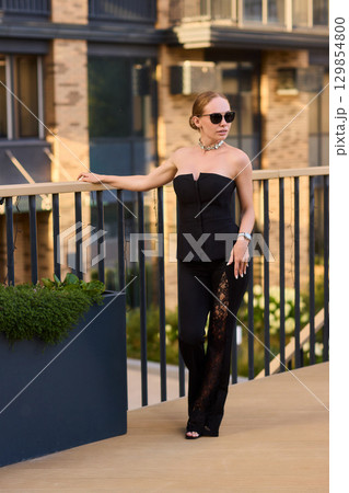 An Elegant Woman in a Stylish Outfit Stands Beautifully at Sunset, Radiating Confidence 129854800