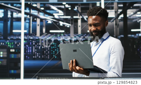 Happy data center admin uses node tree programming on laptop, doing high five with coworker. Smiling server farm worker greeting colleague, reviewing data analysis graph, camera B Happy data center admin uses node tree programming on laptop, doing high five with coworker. Smiling server farm worker greeting colleague, reviewing data analysis graph, camera B 129854823