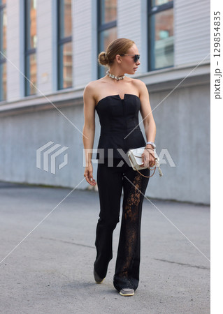 A Stylish and Fashionable Woman Dressed in Elegant Black Attire, Complete with Chic Sunglasses A Stylish and Fashionable Woman Dressed in Elegant Black Attire, Complete with Chic Sunglasses 129854835