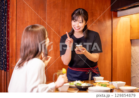 居酒屋　スマホで注文をとる女性スタッフ 129854879