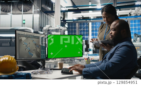 Professionals brainstorming solutions with mockup screen in solar facility, advancing industrial goals through collaboration and corporate responsibility. Team of engineers share insight. Camera A. 129854951