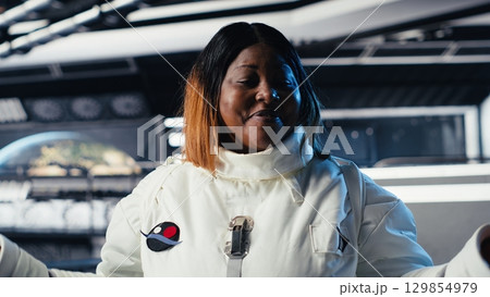 Jolly astronaut waves hand during videocall with Earth command center, documenting results from space experiments. Cosmonaut salutes ground center team, sharing research observations Jolly astronaut waves hand during videocall with Earth command center, documenting results from space experiments. Cosmonaut salutes ground center team, sharing research observations 129854979