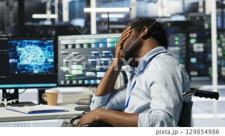 Impatient engineer with paraplegia in data center annoyed by slow AI node tree software. Upset server hub worker with disability frustrated by buggy visual programming tool, camera B Impatient engineer with paraplegia in data center annoyed by slow AI node tree software. Upset server hub worker with disability frustrated by buggy visual programming tool, camera B 129854986