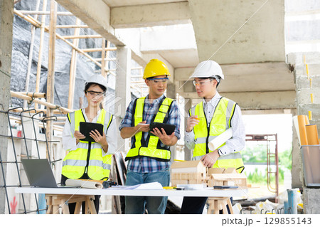 Engineer teams meeting working together wear worker helmets hardhat on construction site in city. Engineer teams meeting working together wear worker helmets hardhat on construction site in city. 129855143