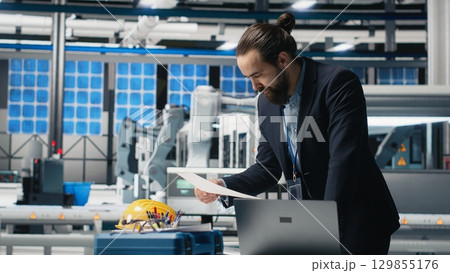 Industrial business expert inspecting alternative energy equipment, demonstrating attention to quality control and photovoltaics manufacturing industry. Solar power plant. Camera B. Industrial business expert inspecting alternative energy equipment, demonstrating attention to quality control and photovoltaics manufacturing industry. Solar power plant. Camera B. 129855176