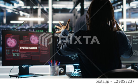 Panicked engineer in AI server facility reacts to hacking incident involving theft of sensitive data. Data center employee alarmed by computer virus triggered by security systems, camera B 129855237