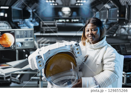 Portrait of smiling cosmonaut in orbital station seeking extraterrestrial life on Mars. Joyous woman working on spaceship testing other planets habitats, doing Martian surface research 129855266