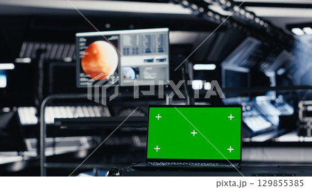 Mockup notebook used for orbital navigation data in cockpit during red planet journey. Green screen laptop used for operating spacecraft control interface next to monitor displaying Mars dashboard 129855385
