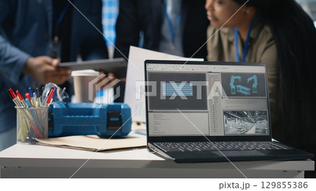 Black engineering specialists reviewing operational workflows in solar power manufacturing plant. Engineers integrating teamwork in alternative energy production line and development. Camera B. 129855386