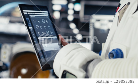 Close up of astronaut using tablet to check logs after completing red planet surface mission. Cosmonaut leaving Mars, updating flight log on device to return home 129855388
