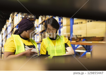 Local brand warehouse team manages e-commerce orders packing, check inventory levels and prepare shipments for local delivery. Employees in hi vis vests coordinate parcel processing. 129855447