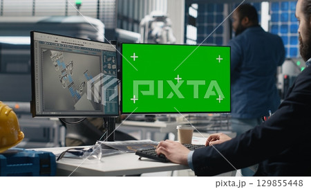 Sustainability expert evaluates solar panel systems next to mockup, working on production line in a modern industrial facility. Guiding operations toward clean energy efficiency. Camera B. 129855448