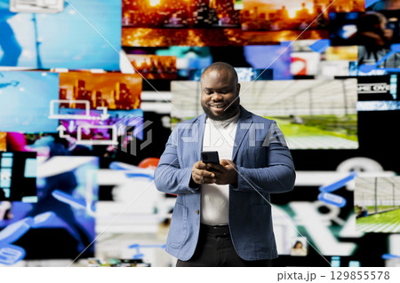 African American person engaged with mobile technology and multimedia feeds, showcasing the evolution of digital presence, communication and app interaction. Modern user interface. African American person engaged with mobile technology and multimedia feeds, showcasing the evolution of digital presence, communication and app interaction. Modern user interface. 129855578