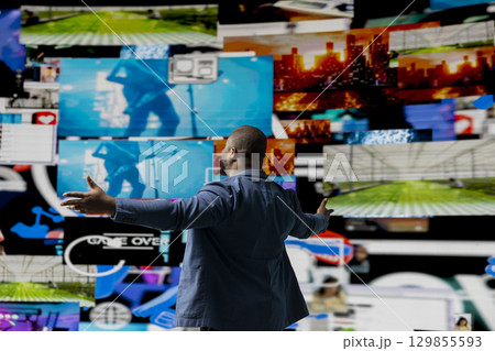 Black social media manager browsing high tech environment with app interfaces, infographics and social networking feeds. Showcases big data on social media platforms, multimedia. Black social media manager browsing high tech environment with app interfaces, infographics and social networking feeds. Showcases big data on social media platforms, multimedia. 129855593