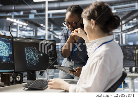Cheerful data center admins doing fist bump, celebrating successful AI implementation. Jolly server hub teamworking coworkers excited after optimal results achieved by artificial intelligence model 129855871