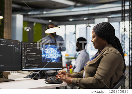 System administrator in office using AI automation scripts to reduce repetitive coding tasks. Woman using artificial intelligence technology on PC in high tech startup workspace System administrator in office using AI automation scripts to reduce repetitive coding tasks. Woman using artificial intelligence technology on PC in high tech startup workspace 129855925