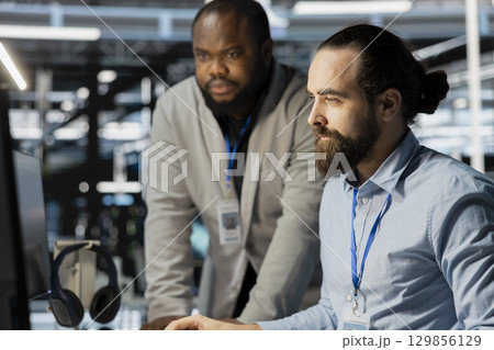 Team of technicians in data center using PC to update storage arrays software, configuring network virtualization. Teamworking colleagues in server room using computer to verify settings 129856129