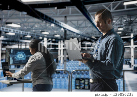 Server farm team of technicians debugging machine learning scripts on laptop, doing AI automatization. Data center programmer and coworker optimizing neural networks, adjusting deep learning models 129856235