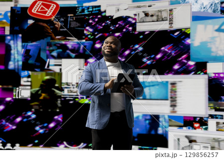 Black young social network user checks dashboards with dynamic screens showcasing social media and networking, highlighting the importance of online engagement and global connection. 129856257