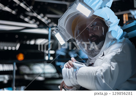 Cosmonaut in starship using communication systems integrated in suit during cosmic journey. Astronaut speaking in telecoms device, studying cosmic origins during long distance space travel 129856281
