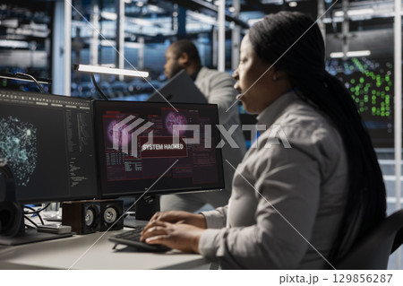 Server farm IT specialist trying to repair compromised hardware after hacker attack. Software developer in data center fighting malicious threat, initiating protocol to protect critical systems 129856287