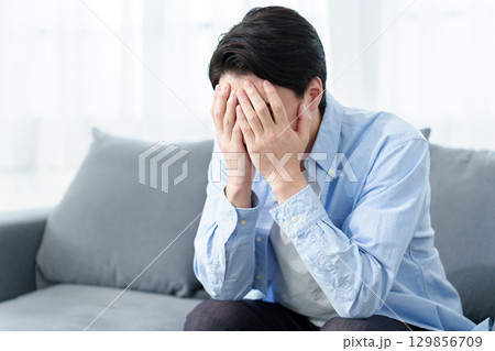 頭を抱えてうずくまる男性 129856709