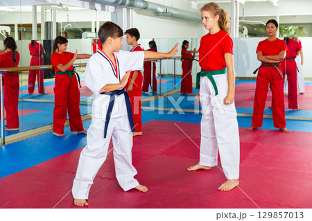 Children sparring in pairs to practice new moves in karate class Children sparring in pairs to practice new moves in karate class 129857013