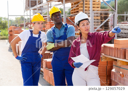 Builders and taskmaster having conversation in warehouse 129857029