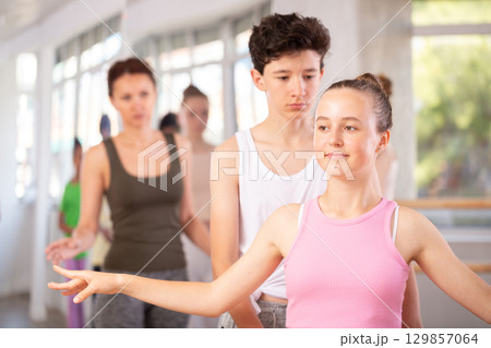 Teenage girl practicing ballet positions in pair with boy in dance studio 129857064